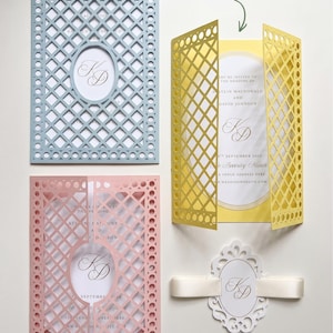 May include: Three laser-cut wedding invitation jackets in light blue, yellow, and pink with a lattice pattern and oval center cutout. A white oval tag with a ribbon and the monogram KD is included. Text reads: Customise to your Color Palette.