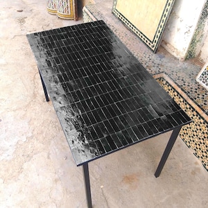 May include: A rectangular black tile-top table with a glossy finish. The table has a black metal frame and four legs. The tabletop is composed of small, rectangular black tiles.