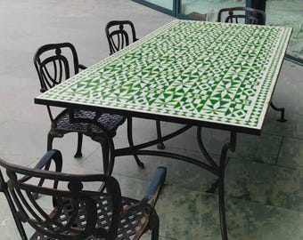 Pode incluir: Conjunto de jantar ao ar livre com uma mesa retangular com tampo de azulejo geométrico verde e branco. A mesa, suportada por uma estrutura de metal preto, é rodeada por quatro cadeiras de metal preto a condizer. Ideal para o jardim.
