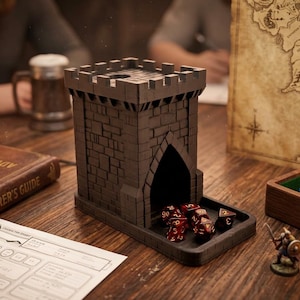 May include: A dark brown, castle-shaped dice tower with a tray, perfect for tabletop gaming. The tower has a brick design and an arched entrance. Several red dice are in the tray. A miniature figurine and a wooden box with dice are also visible.