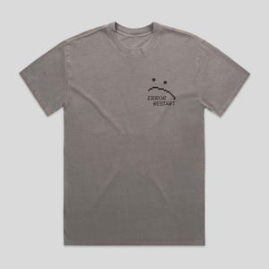 Peut inclure: Un t-shirt gris avec un visage triste pixélisé et le texte "ERROR RESTART" imprimé sur le devant.