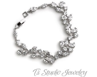 May include: A silver bracelet with a delicate design of clear cubic zirconia stones arranged in a floral pattern.