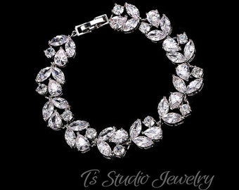 May include: A silver bracelet with a delicate design of clear cubic zirconia stones set in a leaf pattern.