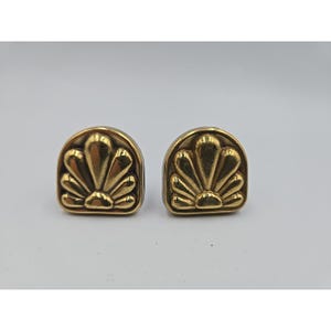 May include: A pair of gold-colored, vintage-style earrings. Each earring features a fan-shaped design within a rounded, half-circle frame. The earrings have a polished finish and are set against a plain background.