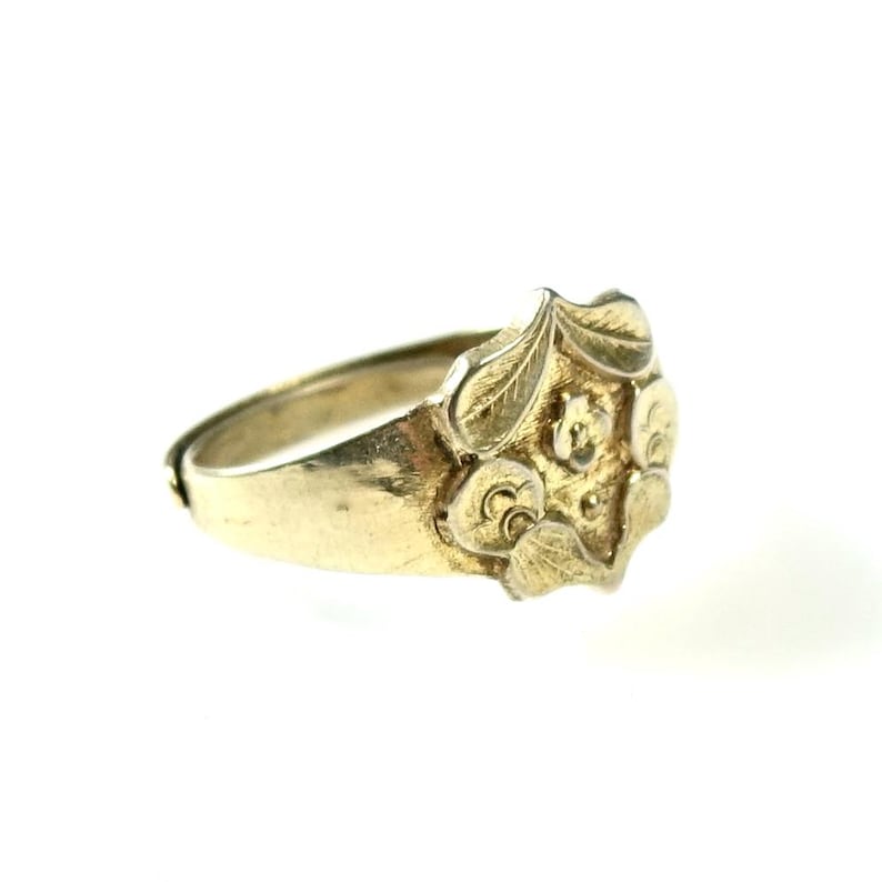 May include: A gold ring with a floral design. The ring is made of solid gold and has a smooth finish.
