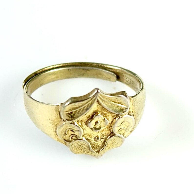 May include: A gold ring with a floral design. The ring is made of metal and has a smooth finish.