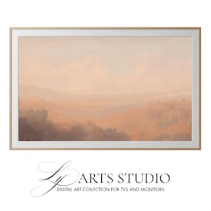 Puede incluir: Pintura de paisaje enmarcada con una paleta de colores cálidos de melocotón, marrón y gris. La obra representa una cordillera brumosa y un cielo nublado. El marco es de color madera clara. El texto "Ly Arts Studio" está en la parte inferior.