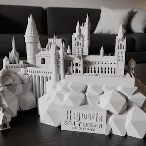 May include: A white 3D printed model of Hogwarts School of Witchcraft and Wizardry, sitting on a rocky base. The model is detailed and includes the iconic towers and spires of the castle.