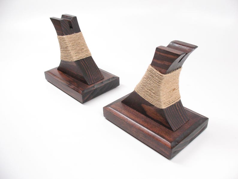 May include: Two dark stained wooden bookends with a curved design. Each bookend has a rectangular base and a curved support wrapped with natural twine. The bookends are displayed on a white background.