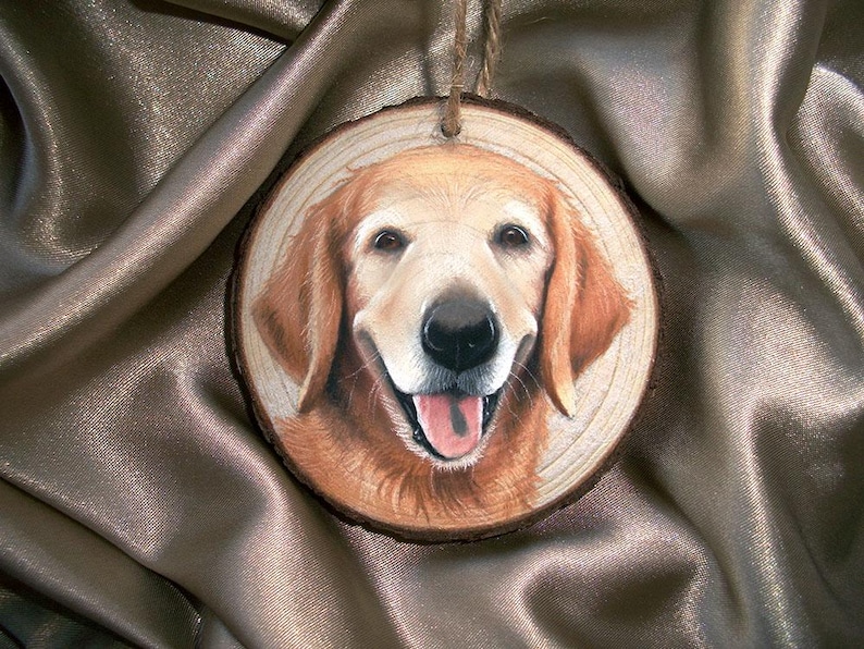 May include: A hand-painted wooden ornament featuring a golden retriever dog with a happy expression. The dog is painted realistically with brown fur and a pink tongue.
