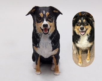 May include: A detailed figurine of a dog, featuring a black, white, and tan coat. The dog is sitting with its mouth open, showcasing a happy expression. An oval-shaped image of the dog is next to the figurine.