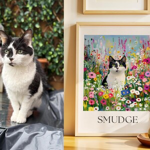 Peut inclure: Un chat noir et blanc est assis &agrave; c&ocirc;t&eacute; d'une impression encadr&eacute;e. L'impression repr&eacute;sente un chat noir et blanc au milieu de fleurs color&eacute;es. Le mot "SMUDGE" est imprim&eacute; au bas du cadre.