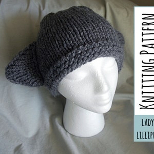 Puede incluir: Sombrero de punto gris con orejeras. El sombrero está en una cabeza de maniquí blanca. El texto "LADY LILLIPUT KNITTING PATTERN" está sobre un fondo azul.