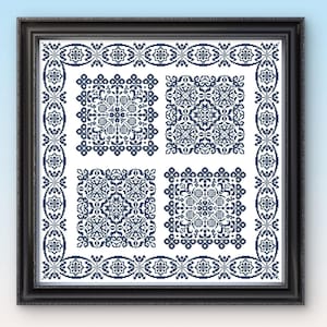 Op de afbeelding: Ingelijst kruissteekkunstwerk met vier ingewikkelde marineblauwe geometrische patronen op een witte achtergrond. De patronen zijn omgeven door een marineblauwe rand met bloemen en geometrische motieven. De lijst is zwart.