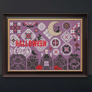 Puede incluir: Arte de punto de cruz enmarcado con temática de Halloween. El diseño presenta un fondo morado con varios motivos de Halloween, incluyendo una luna creciente con un gato negro, lápidas y la palabra "HALLOWEEN" en rojo.