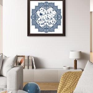 May include: A framed, blue and white Christmas-themed cross-stitch design. The artwork features a circular pattern with a winter village scene, reindeer, and Santa's sleigh. The frame is dark brown, and the artwork is displayed on a white wall.