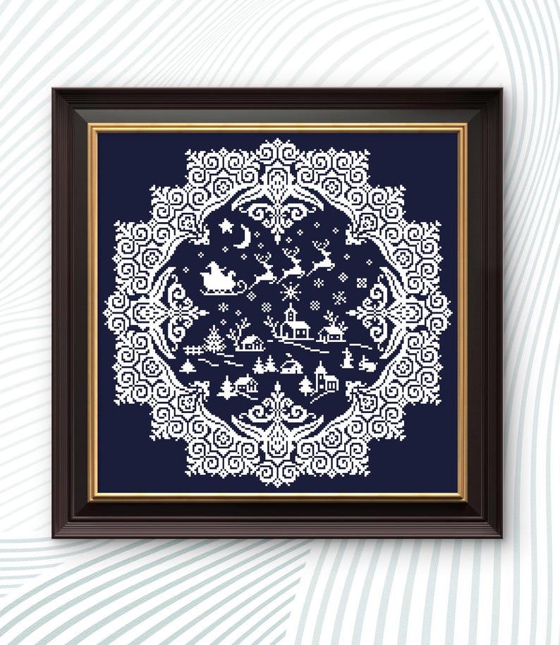 May include: Framed cross-stitch art featuring a winter village scene with Santa's sleigh, reindeer, and snowflakes. The design is white on a navy blue background, framed in a dark brown frame with a gold inner border. The artwork has a circular, ornate border.