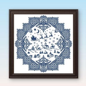 May include: Framed cross-stitch artwork featuring a winter village scene in shades of blue and white. The design includes Santa in his sleigh, reindeer, houses, trees, and snowflakes, surrounded by a decorative border. The frame is dark brown.