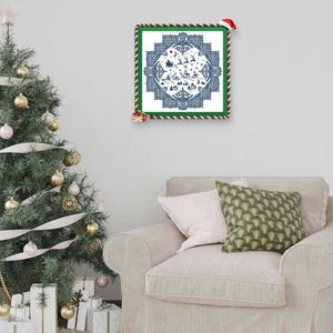 May include: A framed Christmas-themed print with a blue and white design featuring Santa's sleigh, reindeer, and a village scene. The frame is green with red and white striped trim. A Christmas tree and presents are in the background.