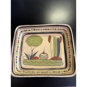 May include: Hand-painted square ceramic tray with a desert landscape design. The tray features a beige background with a green tree, cactus, and a decorative border with brown, green, and red dots. The tray is perfect for serving snacks or as a decorative piece.