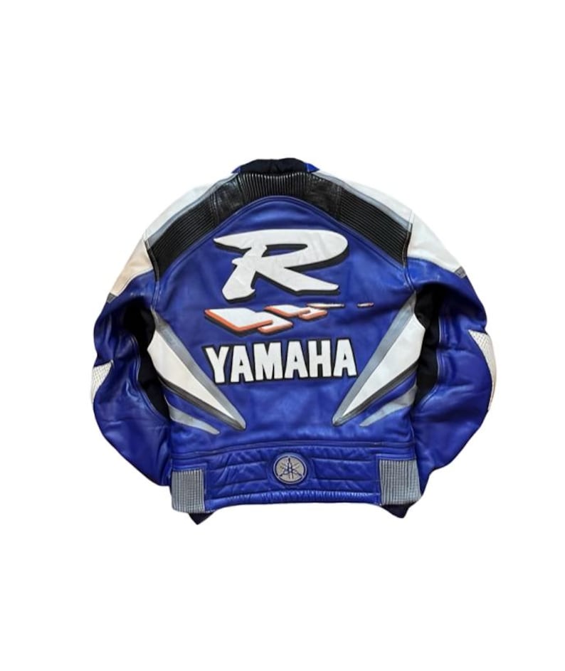 K&ouml;nnte beinhalten: Blaue und wei&szlig;e Motorradjacke aus Leder mit dem Yamaha-Logo auf dem R&uuml;cken. Die Jacke hat einen schwarzen Kragen und wei&szlig;e Akzente an den &Auml;rmeln. Auf der R&uuml;ckseite der Jacke befindet sich ein gro&szlig;es wei&szlig;es "R" und das Wort "YAMAHA".