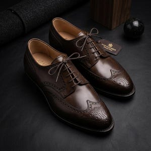 May include: A pair of dark brown leather oxford shoes featuring intricate brogue detailing, a wingtip toe cap, and thin matching laces. A small rectangular tag attached to the right shoe displays the text Fine Footwear in gold lettering.