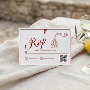 May include: White RSVP card with red text and a red border. The card features the word "RSVP" in elegant script, along with the text "Your reply is requested by 17 Aug, 2025". A bow and champagne illustration are also present.