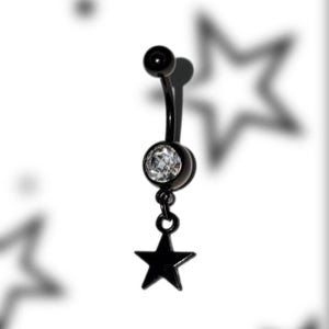 Può includere: Un piercing all'ombelico nero con un ciondolo a forma di stella. Il bilanciere curvo presenta una gemma trasparente al centro e un pendente a forma di stella pendente. Il gioiello è posto su uno sfondo bianco.