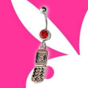 May include: A silver-colored belly button ring with a red jewel and a charm shaped like a flip phone. The flip phone charm is open, revealing the inside details. The ring has a curved barbell design.