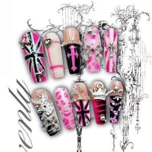 May include: A collection of artificial nails with various designs. The nails feature pink, black, and white colors, with accents like stars, bows, crosses, and rhinestones. Some nails display Union Jack patterns, lip prints, and the word "Princess".