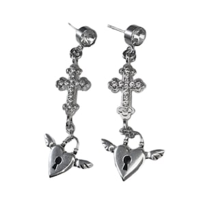 May include: A pair of silver-coloured drop earrings. Each earring has a clear, round stud, a decorative cross, and a heart-shaped charm with a keyhole and small wings. The earrings are designed with intricate details and a gothic aesthetic.