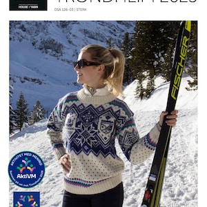 May include: A woman in a patterned sweater with the text "VM GENSER TRONDHEIM 2025" is holding a ski. The sweater features white, blue, and purple patterns. The background shows a snowy mountain.
