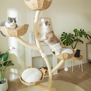 May include: A multi-level cat tree with woven baskets and plush cushions. Two cats are interacting with the tree, one resting and the other playing with a dangling toy. The tree is made of natural materials and has a neutral color palette.