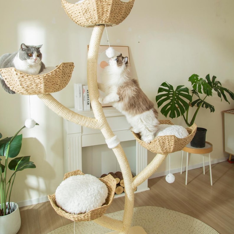 May include: A multi-level cat tree with woven baskets and plush cushions. Two cats are interacting with the tree, one resting and the other playing with a dangling toy. The tree is made of natural materials and has a neutral color palette.