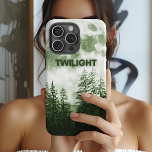 May include: A phone case featuring a green forest scene with a full moon and the word "TWILIGHT" in green lettering. The case has a white background and a dark green forest design.