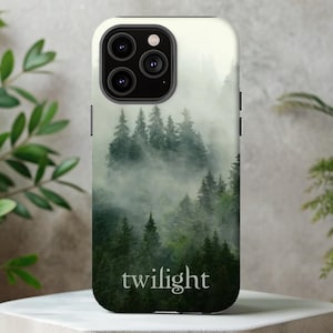 May include: A phone case featuring a misty forest scene with tall green trees. The word "twilight" is printed in white at the bottom. The case has a white border and a black camera module.