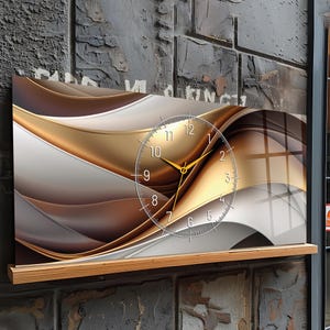 May include: A rectangular wall clock with a contemporary design. The clock face is transparent with gold hands and numerals. The background features flowing, abstract shapes in gold, white, and brown tones. The clock is mounted on a wooden shelf.
