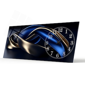 May include: A rectangular wall clock with a contemporary design. The clock face is white with black numerals. The background features a blue and gold abstract design. The clock is angled, highlighting its depth and design.