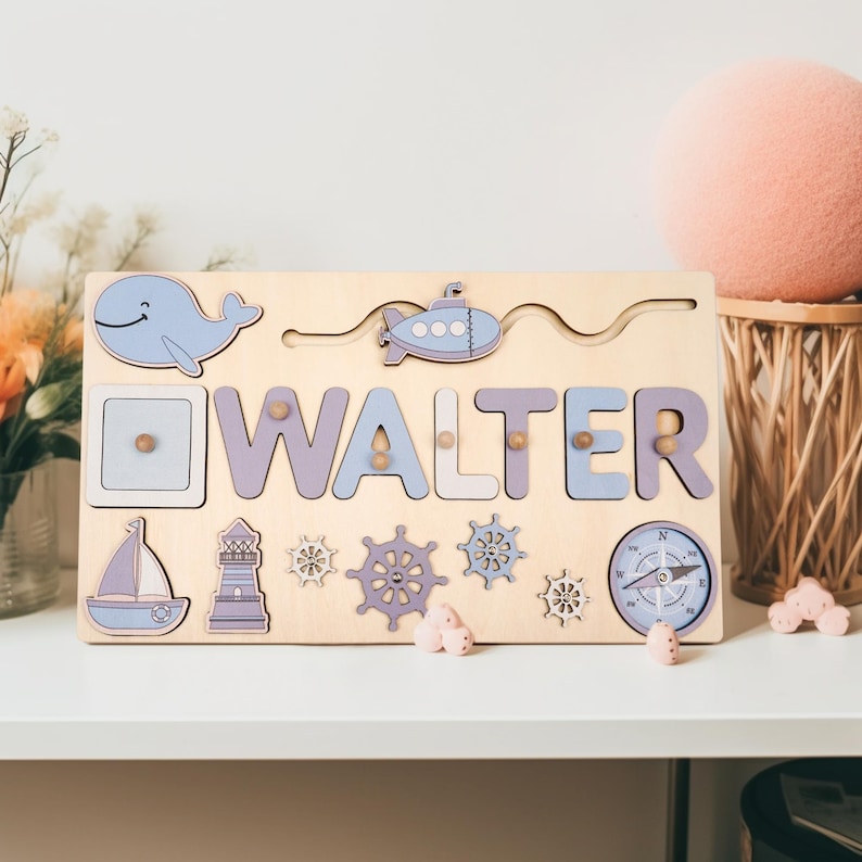 K&ouml;nnte beinhalten: Holzpuzzle mit dem Namen "WALTER" in lila und blauen Buchstaben. Das Puzzle zeigt nautische Formen wie einen Wal, ein Segelboot, einen Leuchtturm und einen Kompass. Das Puzzle befindet sich auf einem hellen Holzgrund.