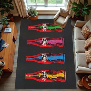 Puede incluir: Una alfombra en blanco y negro con cinco botellas de Coca-Cola impresas en ella. Las botellas est&aacute;n dispuestas verticalmente y son de diferentes colores, incluyendo rojo, azul, verde y amarillo. La alfombra est&aacute; sobre un suelo de madera con un sof&aacute; y un mueble de TV en el fondo.