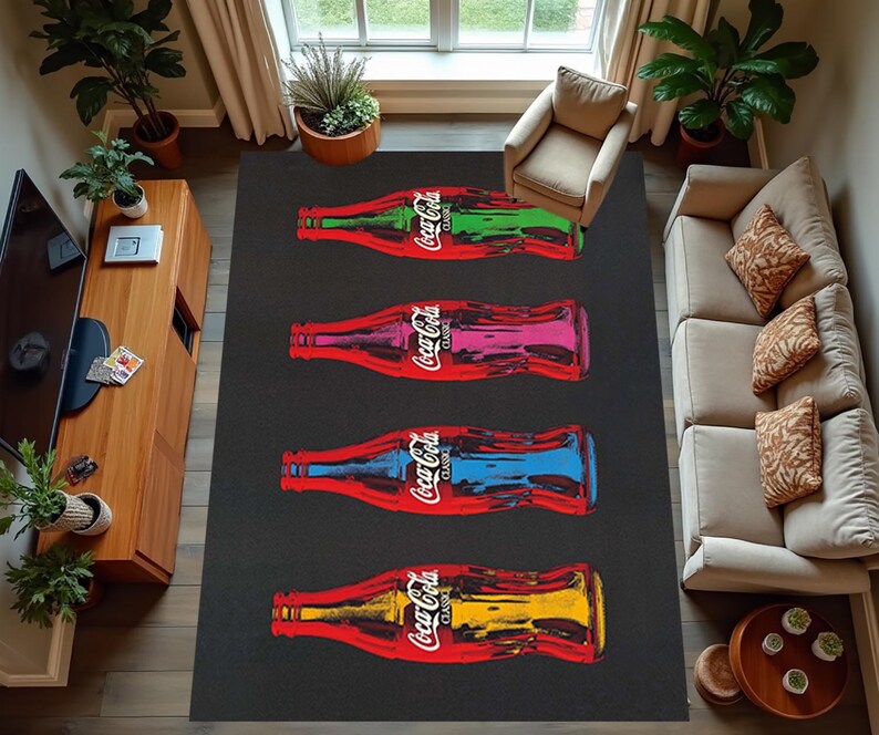 Puede incluir: Una alfombra en blanco y negro con cinco botellas de Coca-Cola impresas en ella. Las botellas est&aacute;n dispuestas verticalmente y son de diferentes colores, incluyendo rojo, azul, verde y amarillo. La alfombra est&aacute; sobre un suelo de madera con un sof&aacute; y un mueble de TV en el fondo.