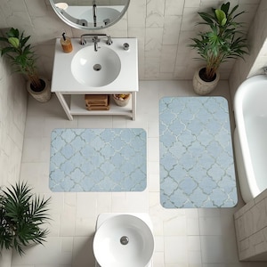 May include: Bathroom scene featuring a light blue patterned bath mat set. The set includes a rectangular mat and a smaller, matching mat. The bathroom has white tile flooring, a white sink, and a bathtub.
