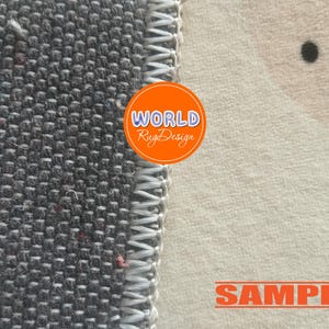 May include: Close-up of a rug with a gray woven texture on the left and a cream-colored patterned section on the right. The rug has a white stitched border. An orange circle with the text "WORLD Rug Design" is visible. The word "SAMPLE" is also visible.