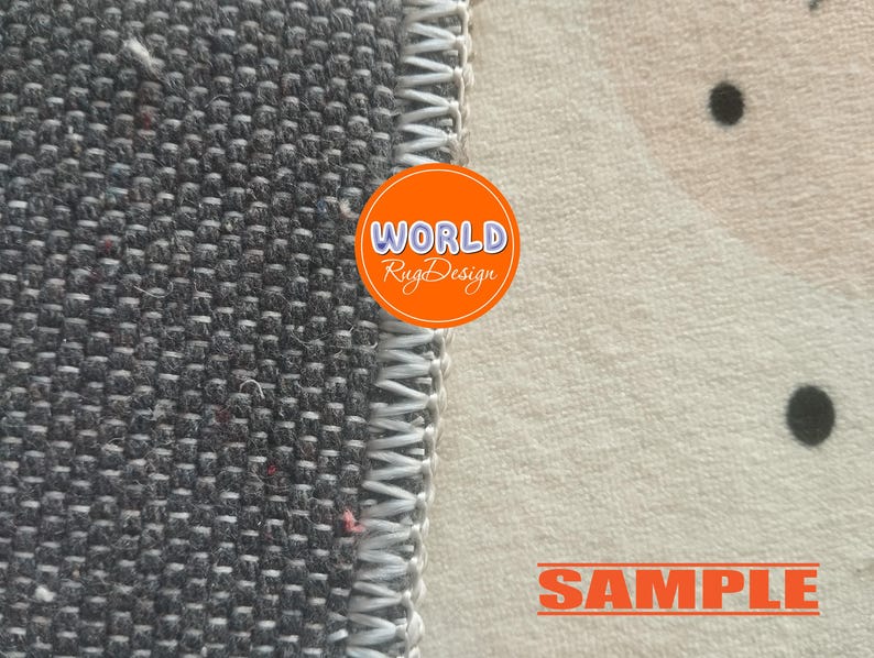 May include: Close-up of a rug with a gray woven texture on the left and a cream-colored patterned section on the right. The rug has a white stitched border. An orange circle with the text "WORLD Rug Design" is visible. The word "SAMPLE" is also visible.