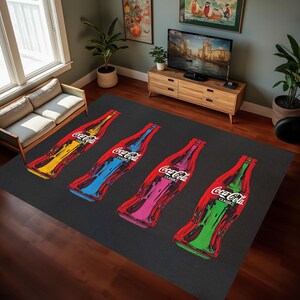 Puede incluir: Una alfombra negra con cuatro botellas de Coca-Cola impresas en ella. Las botellas son de diferentes colores: amarillo, azul, rosa y verde. Las botellas est&aacute;n dispuestas horizontalmente a trav&eacute;s de la alfombra.