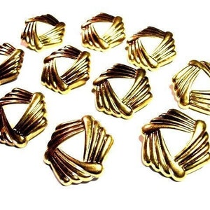 May include: Ten gold-toned metal decorative embellishments with a geometric design. Each embellishment features a triangular shape with a criss-cross pattern.