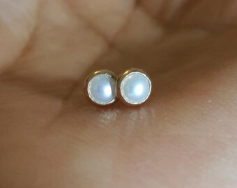 May include: A pair of small, white pearl stud earrings with gold settings.