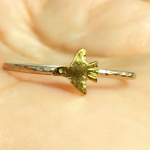 Op de afbeelding: Een zilveren ring met een gehammerde afwerking en een gouden duifbedel.