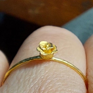 May include: A gold ring with a small, textured flower design.