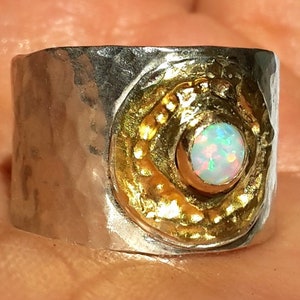 May include: A silver ring with a hammered texture and a gold-toned bezel set with a white opal gemstone.